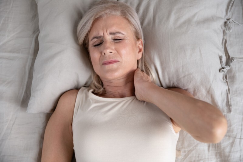 woman laying in bed with neck pain